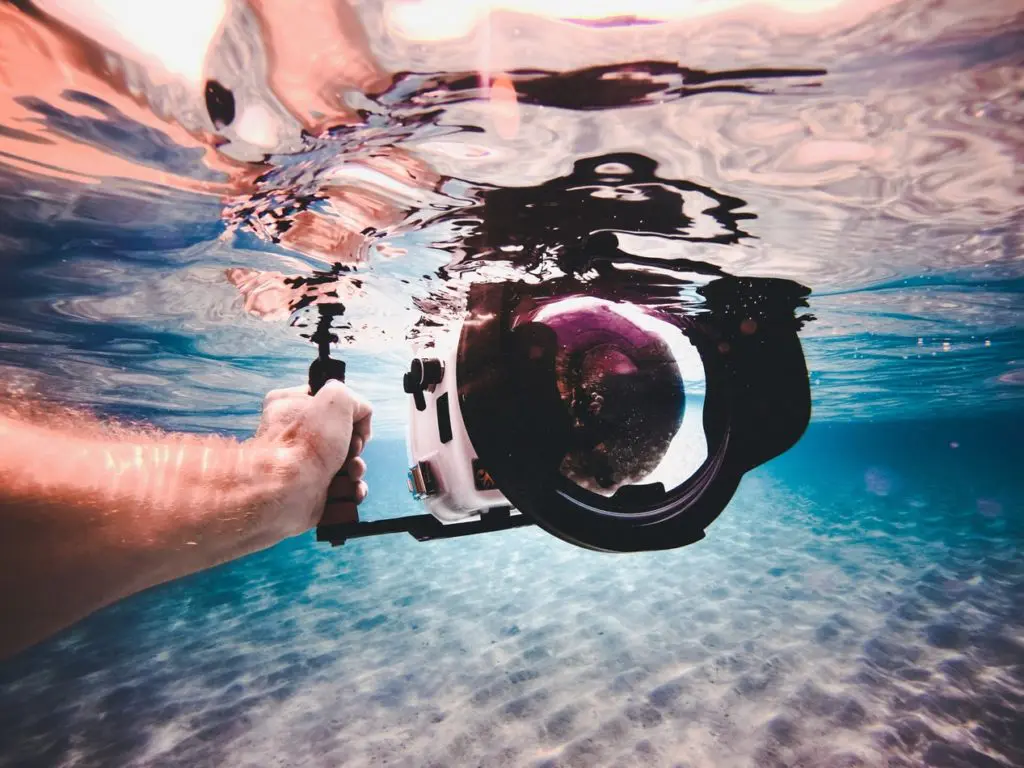 a person's hand holding a ball above water